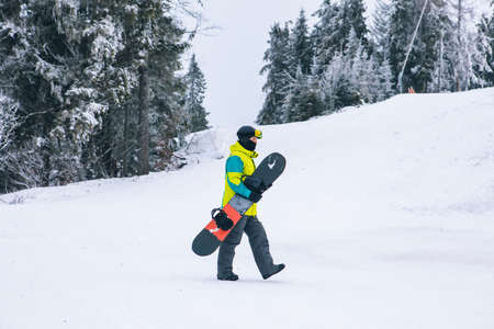 man with snowboard walking by snowed hill winter activities