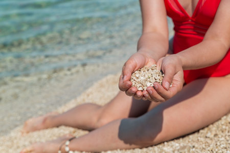 woman sitting at sea beach playing with rocks. summer vacationの写真素材