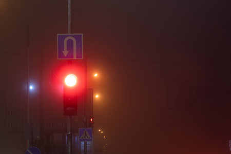 red traffic light in night city fog