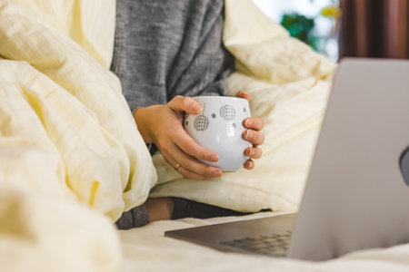 woman hands close up holding mug of coffee near laptop copy spaceの写真素材