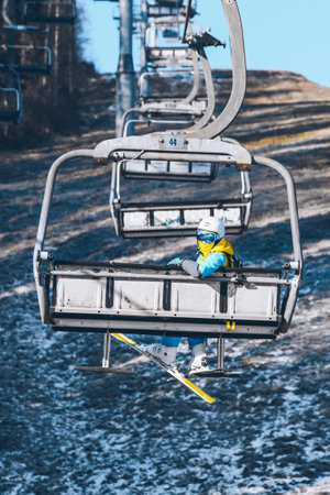 woman going up by chairlift to ski winter mountains