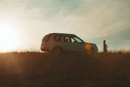 woman silhouette near suv car on sunset copy space