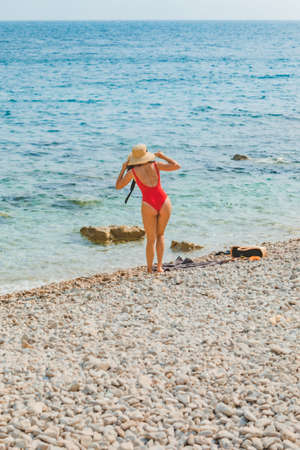 young pretty woman in straw hat at sea beach summer vacation red swimsuitの写真素材