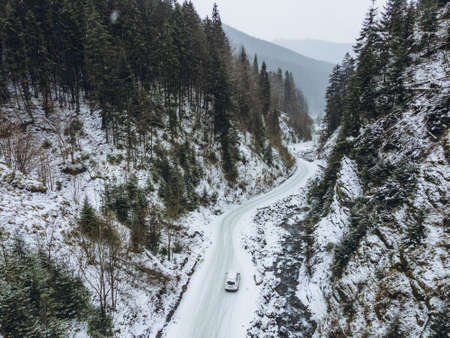 aerial view of car moving by canyon at snowed winter copy space