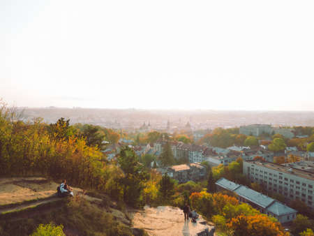 couple sitting on the cliff enjoying view of sunset above autumn city. copy space