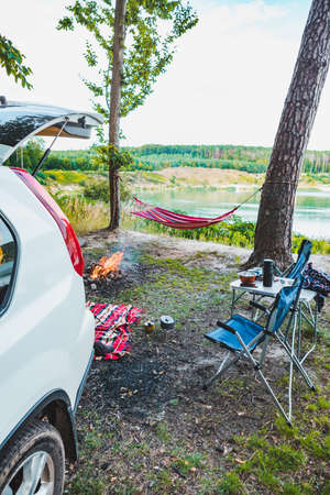 suv car at lake beach camping fire and hammock between trees summer timeの写真素材