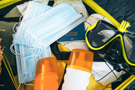 yellow bag full of clothing and passport with medical mask on the top summer 2021の写真素材