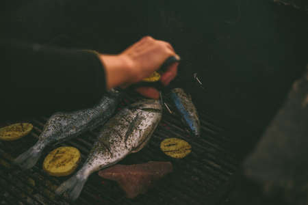 cooking fish and potatoes on grill outdoorsの写真素材