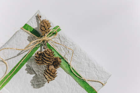 present gift box wrapped with white paper and green ribbon top view