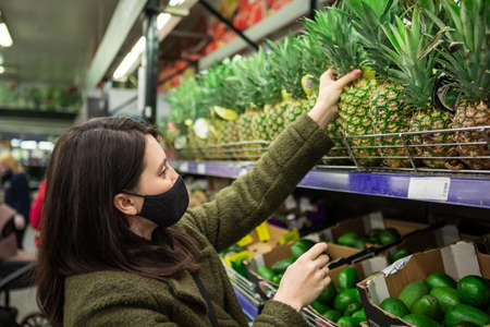 woman choosing fruits pineapple at grocery store