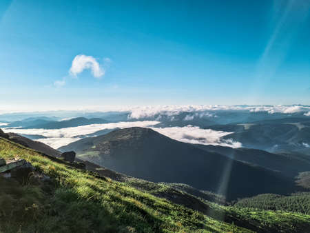 summer view from mountain peak to blue sky with clouds below