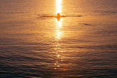strong man swimming in sea at sunrise. summer vacationの写真素材
