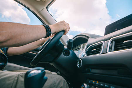 man hands on steering wheel inside view car travel sunny day