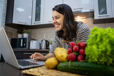 woman cooking checking recipe at laptopの写真素材