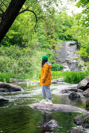 hiker woman in yellow raincoat enjoying view of river in canyon beauty in nature