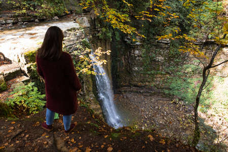 woman looking at waterfall autumn fall season hiking concept