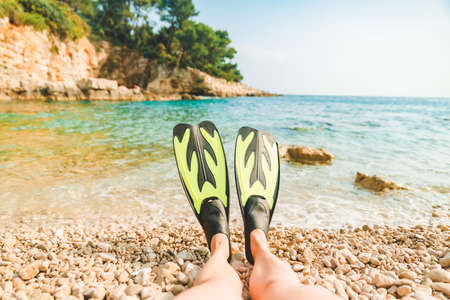 woman legs in flippers at beach sea on background copy space