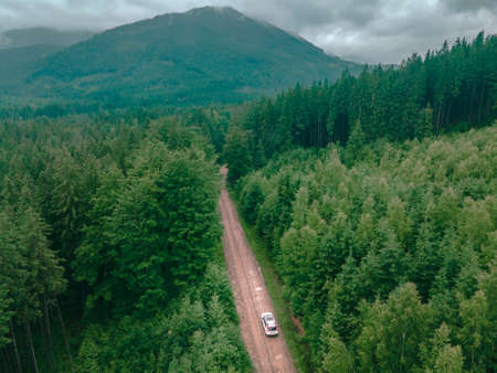aerial view of carpathian mountains overcast weather suv car on trail road copy spaceの写真素材