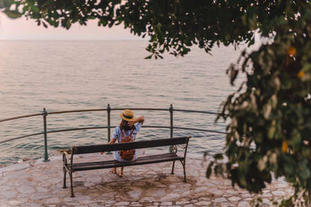 woman sitting on bench and looking at the sea copy spaceの写真素材
