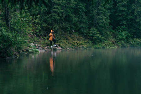 woman hiker in yellow raincoat at lake beach mountains forestの写真素材