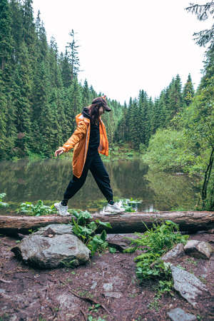 woman hiker with backpack in yellow raincoat looking at mountain lake copy spaceの写真素材