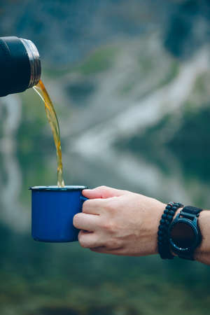 pouring tea from to cup hiking concept lake with mountains on background warm up drinkの写真素材