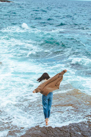 woman walking by rocky beach in wet jeans barefoot. summer sea vacationの写真素材
