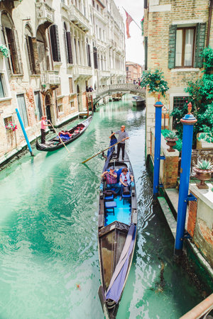 Italy, Venice - May 25, 2019: people at gondola taking tour by canal summer vacationの写真素材