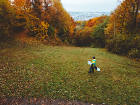 snowboarder waiting for ski season standing on autumn slopeの写真素材
