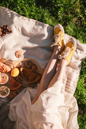 woman legs on blanket having picnic on sunset food drink outdoors summertimeの写真素材