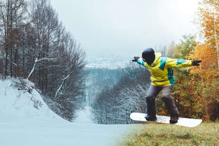 snowboarder waiting for ski season standing on autumn slopeの写真素材
