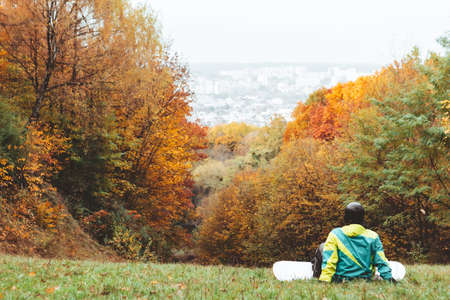 snowboarder waiting for ski season standing on autumn slope