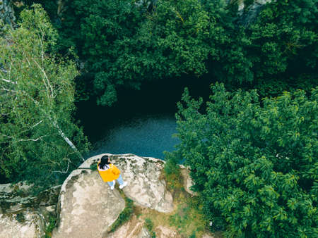 woman sitting on the top enjoying view of canyon river forestの写真素材