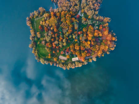 aerial view of autumn forest with lake sky reflected in waterの写真素材