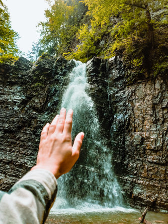 woman hand waterfall on background summertime hiking conceptの写真素材