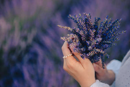 woman in white dress holding bouquet of lavender flowers close upの写真素材