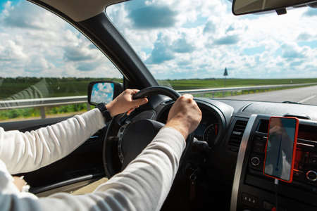 man hands on steering wheel cloudy sunny day copy spaceの写真素材