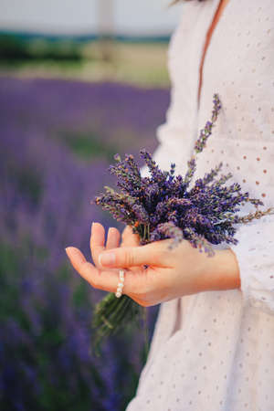 woman in white dress holding bouquet of lavender flowers close upの写真素材