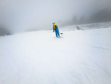 young woman skier sliding down by snowed slope winter mist weather copy space.の写真素材