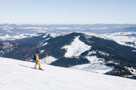 man snowboarder at the top of the slope. beautiful winter mountains. winter vacation. copy space. extreme sportの写真素材