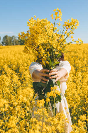 beautiful woman standing in rapeseed field summertime