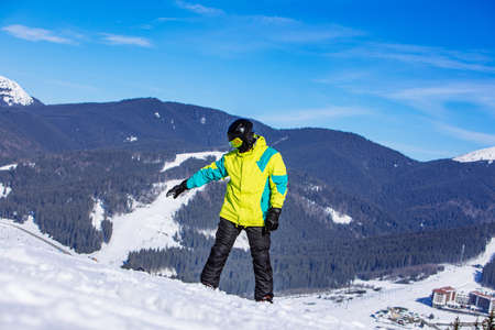 man on the top of the hill with snowboard in sunny day. winter mountains