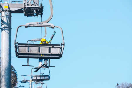 woman going up by chairlift to ski winter mountains