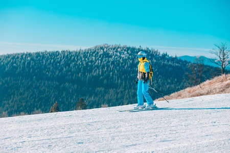 woman skiing down by winter slope mountains on backgroundの写真素材