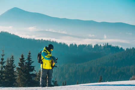 man walking by hill with snowboard mountains on backgroundの写真素材