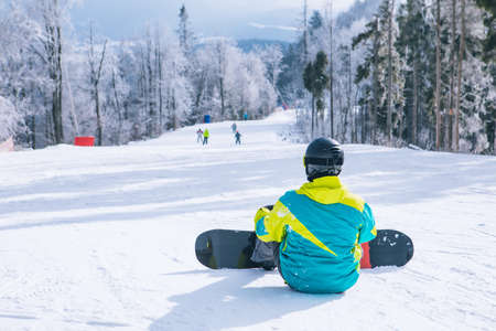 man sitting on the top of the hill enjoying view. snowboarding. winter sport activities. copy spaceの写真素材