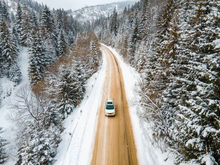 aerial view of the car on snowed road in mountains winter season