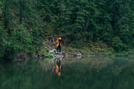 woman hiker in yellow raincoat at lake beach mountains forestの写真素材