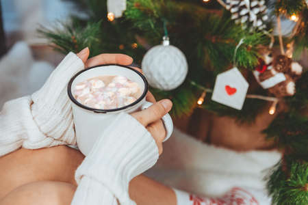 woman hands holding coffee mug near christmas tree copy spaceの写真素材