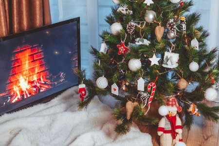Lviv, Ukraine - December 15, 2021: view of fireplace at screen. tv near christmas tree copy space